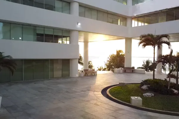 Explanada del Centro Empresarial Cancún al atardecer, con palmeras y vista al mar